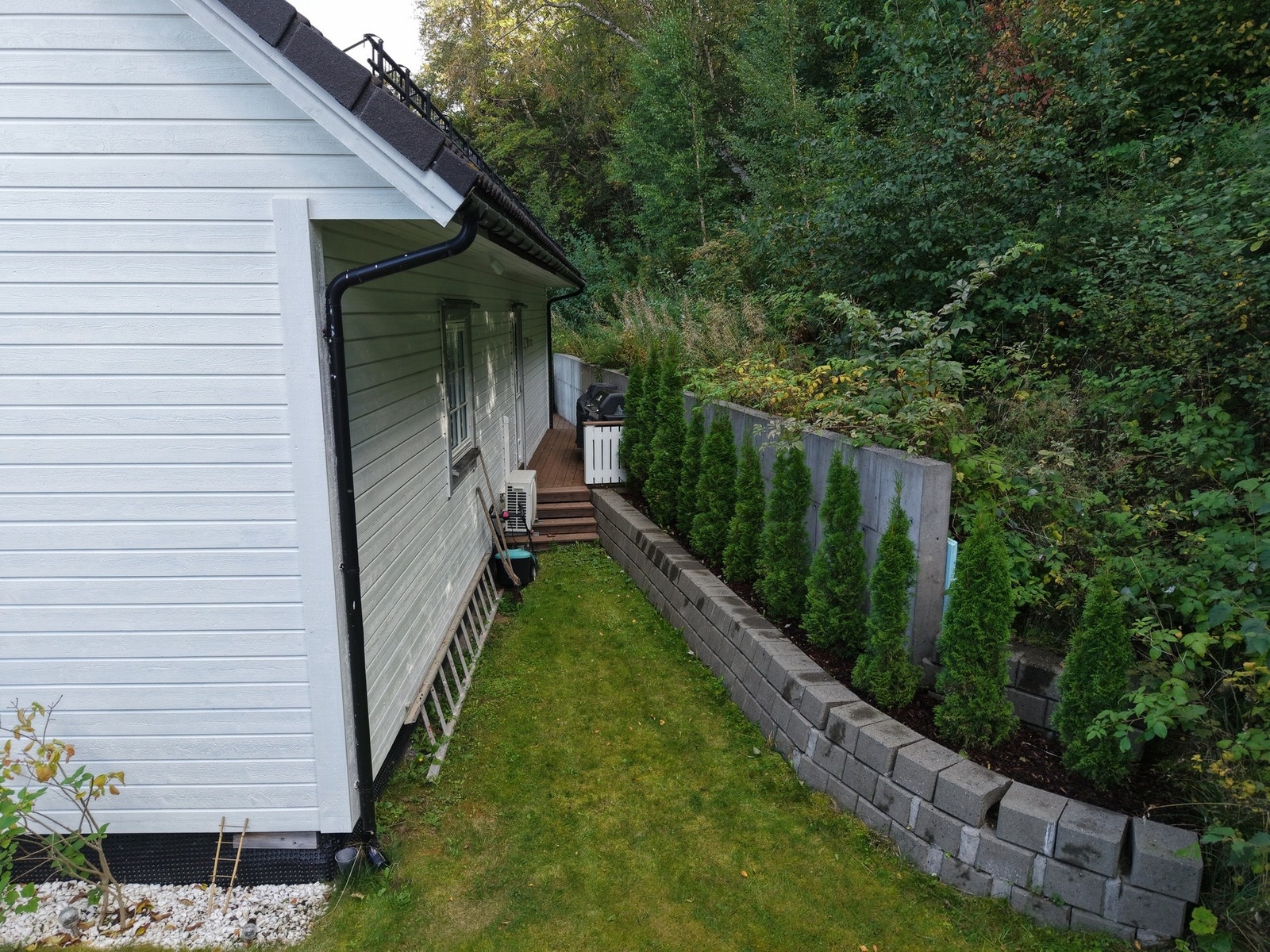 Skjermet og pent opparbeidet tomt grensende opp mot en skog. Galleribilde