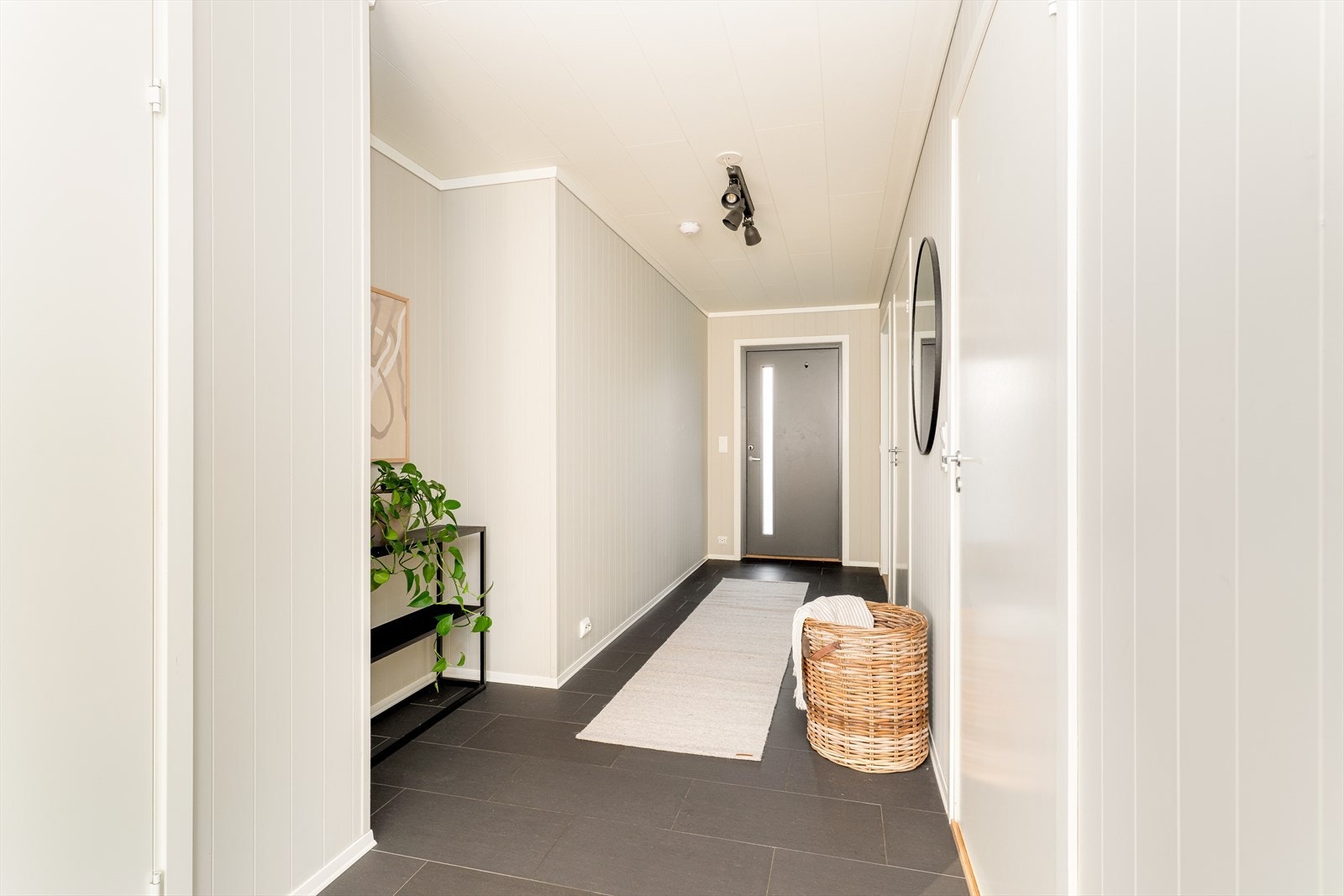 Med adkomst fra det hyggelige inngangspartiet kommer man inn i et lys og romslig entre/gang hvor det er fliser på gulv. Ytterdøren har glassfelt som tilfører rommet lys. I entréen er det god plass til sko- og ytterklær. Galleribilde