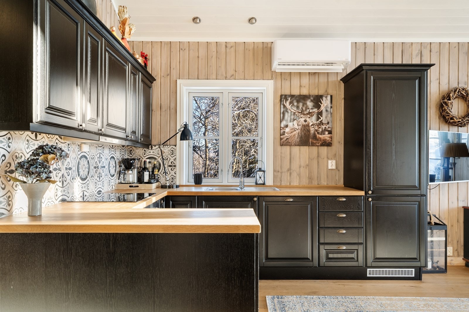 Delikat kjøkken med svart innredning med trestruktur og benkeplate i heltre Galleribilde