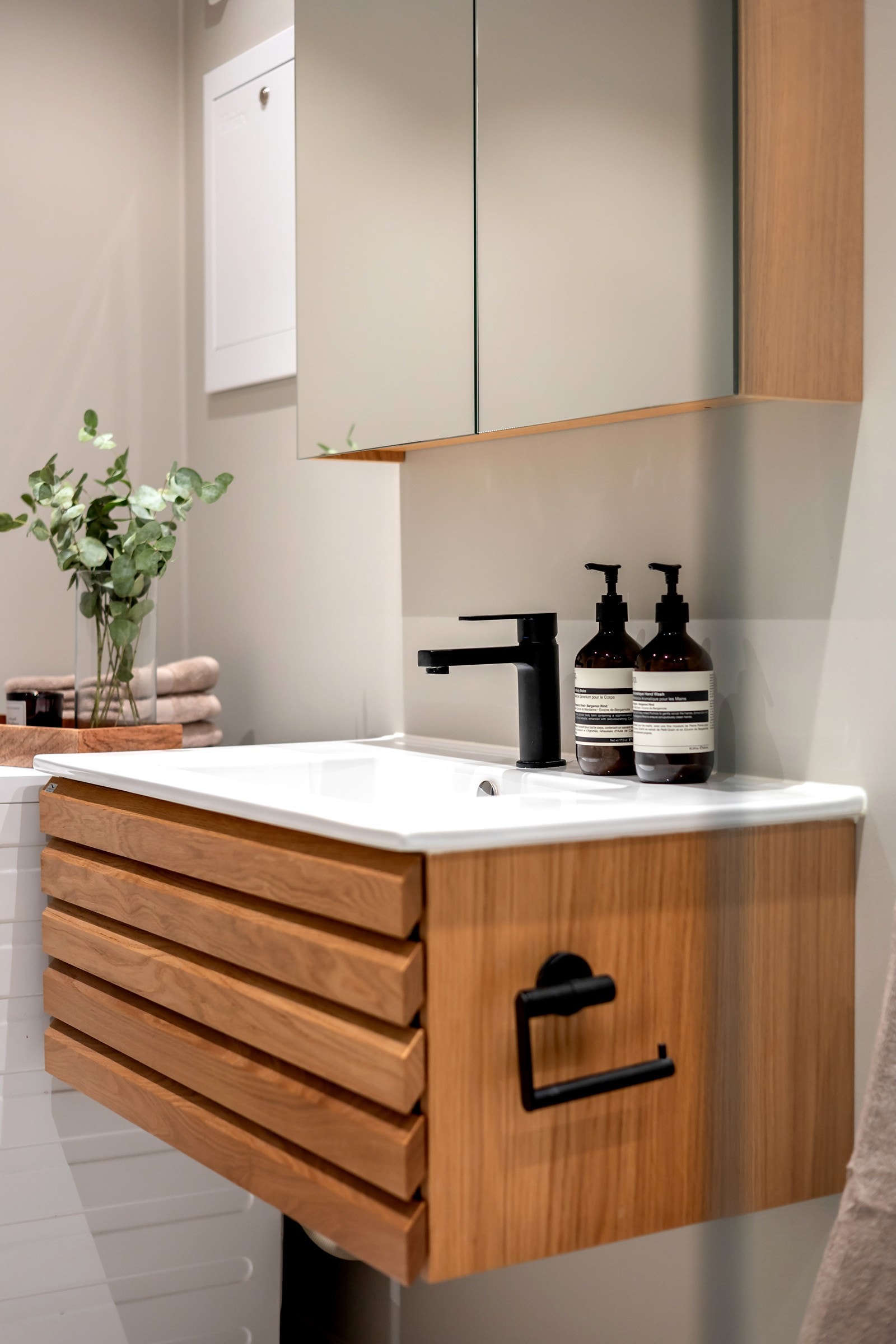 Rommet er innredet med hvit servant over skuffeseksjon, praktisk speilskap med belysning og toalett Galleribilde