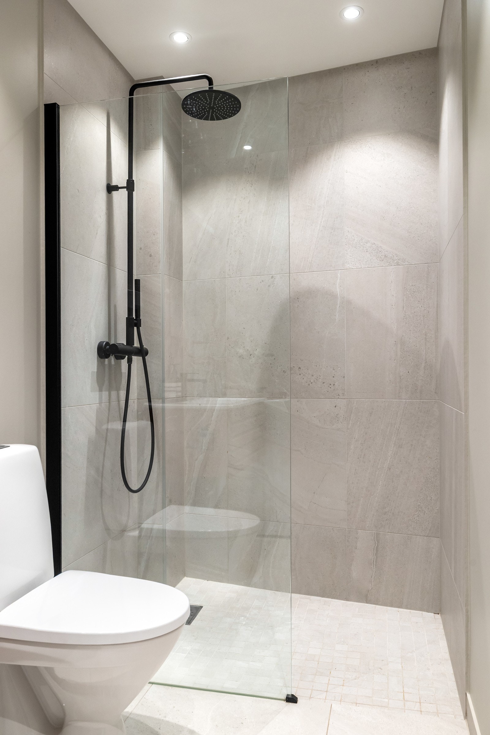 Videre har badet dusjhjørne med glassdør, regnfallsdusj og håndholdt dusj Galleribilde