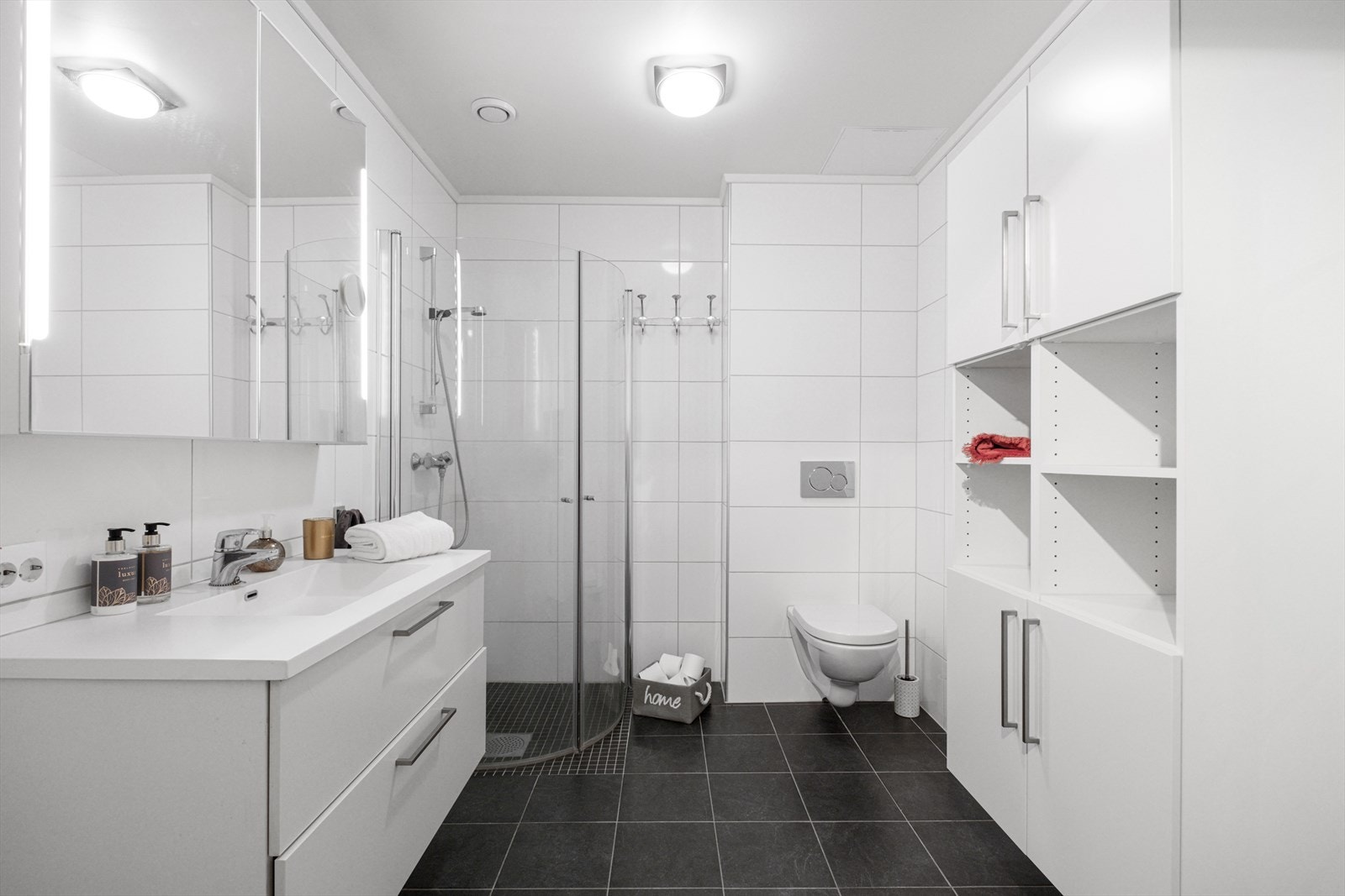 Badet er utstyrt med dusjvegger, vegghengt toalett og innredning med servant samt opplegg for vaskemaskin. Galleribilde