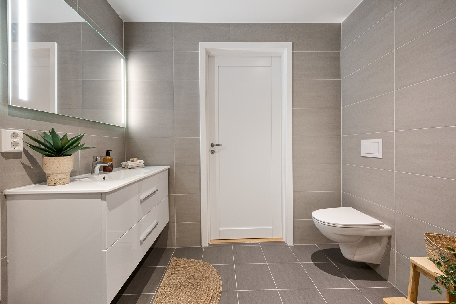 Baderomsinnredning med skuffer i hvit utførelse med glatte fronter, heldekkende servant, ett-greps batteri og tilhørende speil med lys Galleribilde