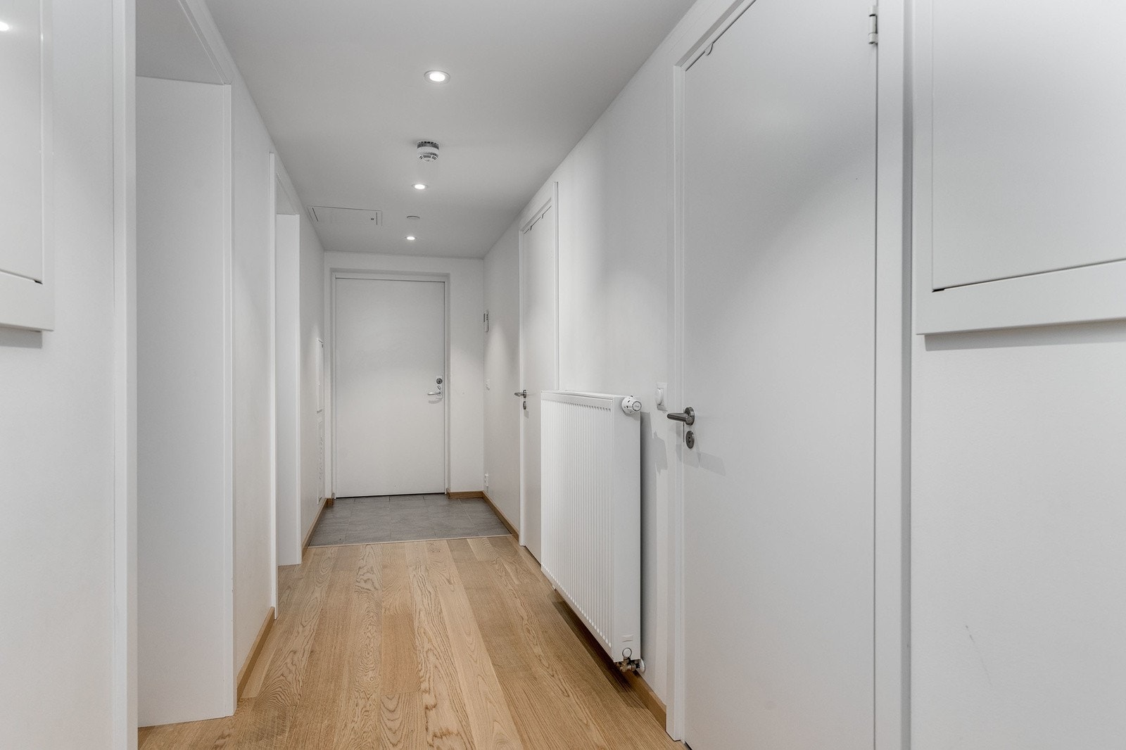 Tiltalende entre med tidsriktige fliser på gulv ved inngangsdør, som gir et godt førsteinntrykk av leiligheten. Varmekabler i flislagt del av entré. Det er montert dørcalling ved inngangsdøren. Galleribilde