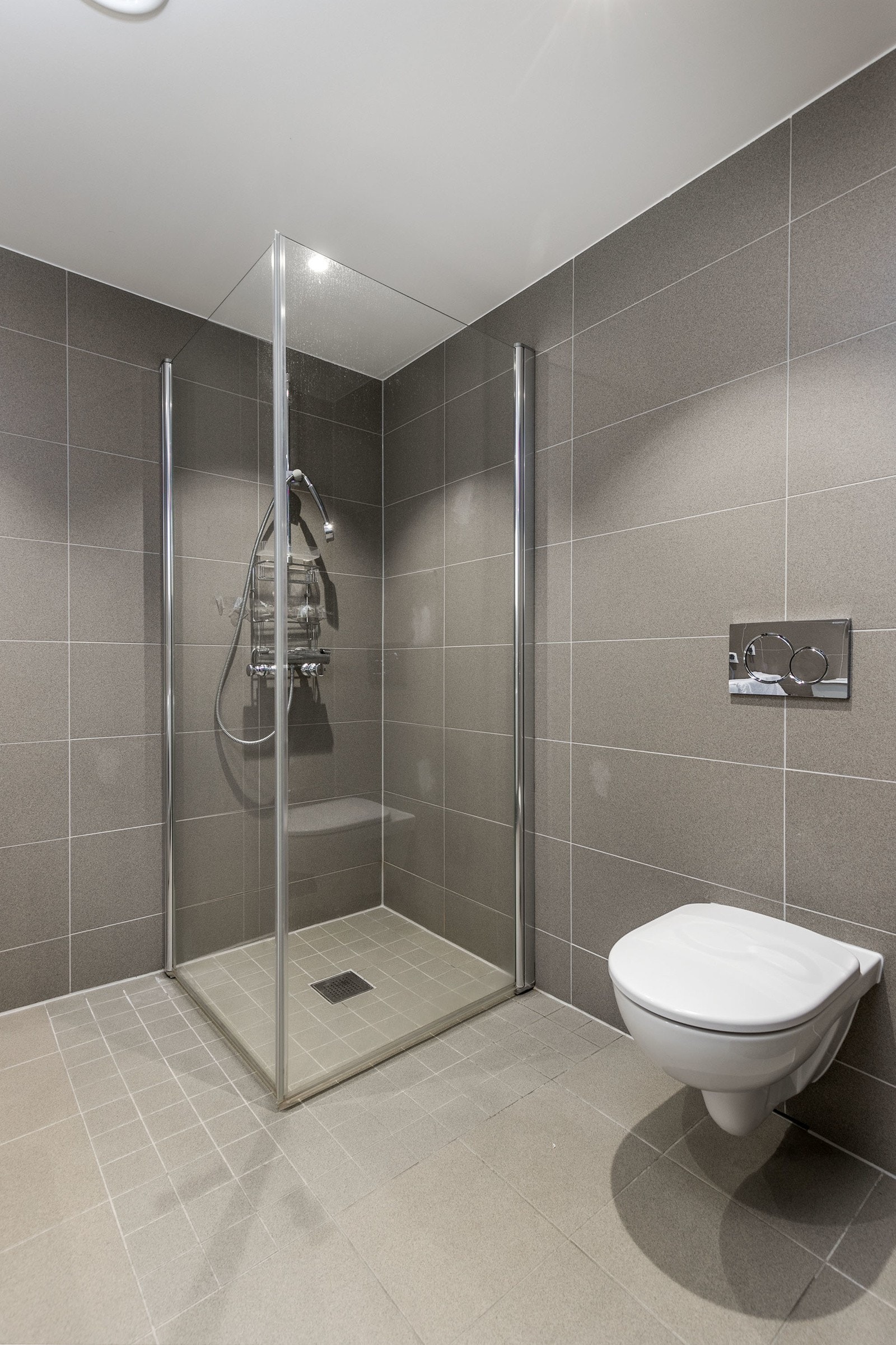 Separat dusjhjørne med hånddusj og innfellbare dusjvegger i glass. Rommet har opplegg og plass for vaskemaskin. Galleribilde