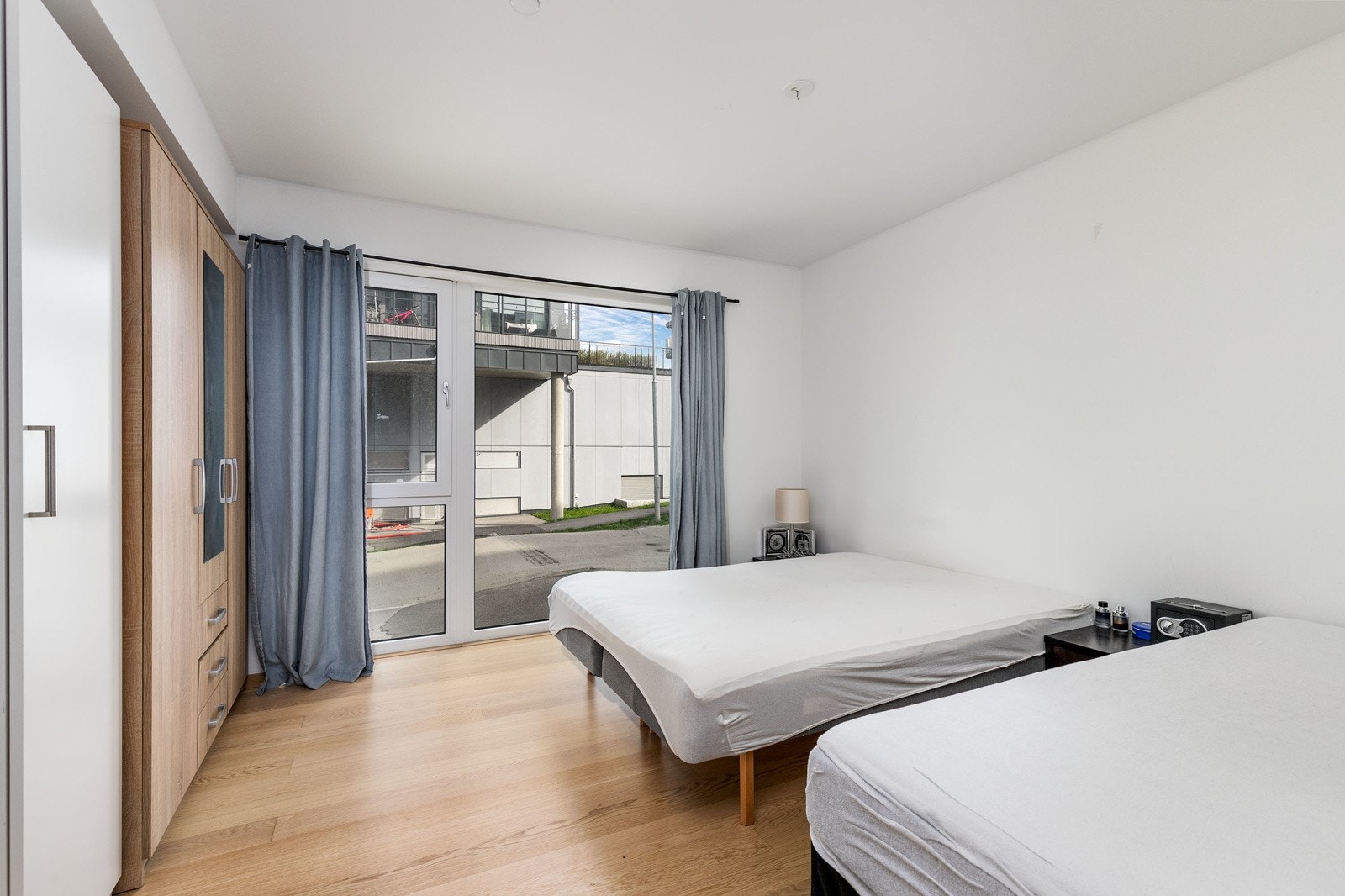 Hovedsoverommet har lysmalte veggflater, enstavs hvitpigmentert parkett på gulv og et stort vindu som slipper inn rikelig med lys Galleribilde