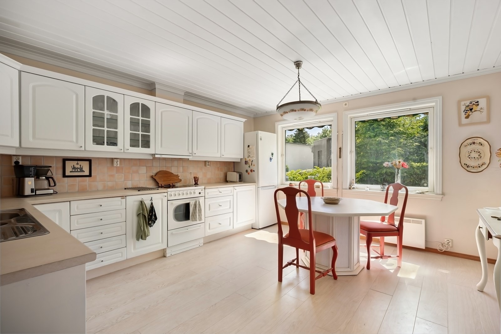 Romslig kjøkken som har svært god skap og benkeplass. Det er fliser mellom kjøkkenbenk og overskap. Galleribilde