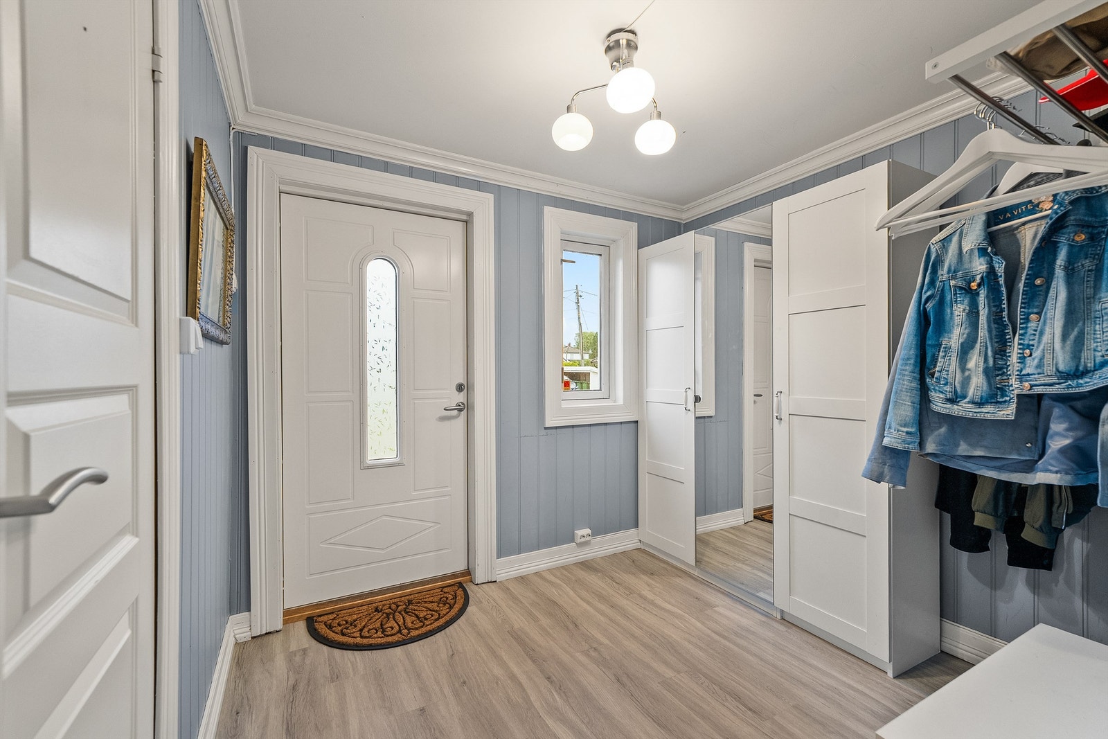 Det er en koselig entré i boligen med malt stående panel på vegg, og det er god plass til garderobeskap og hengmuligheter Galleribilde