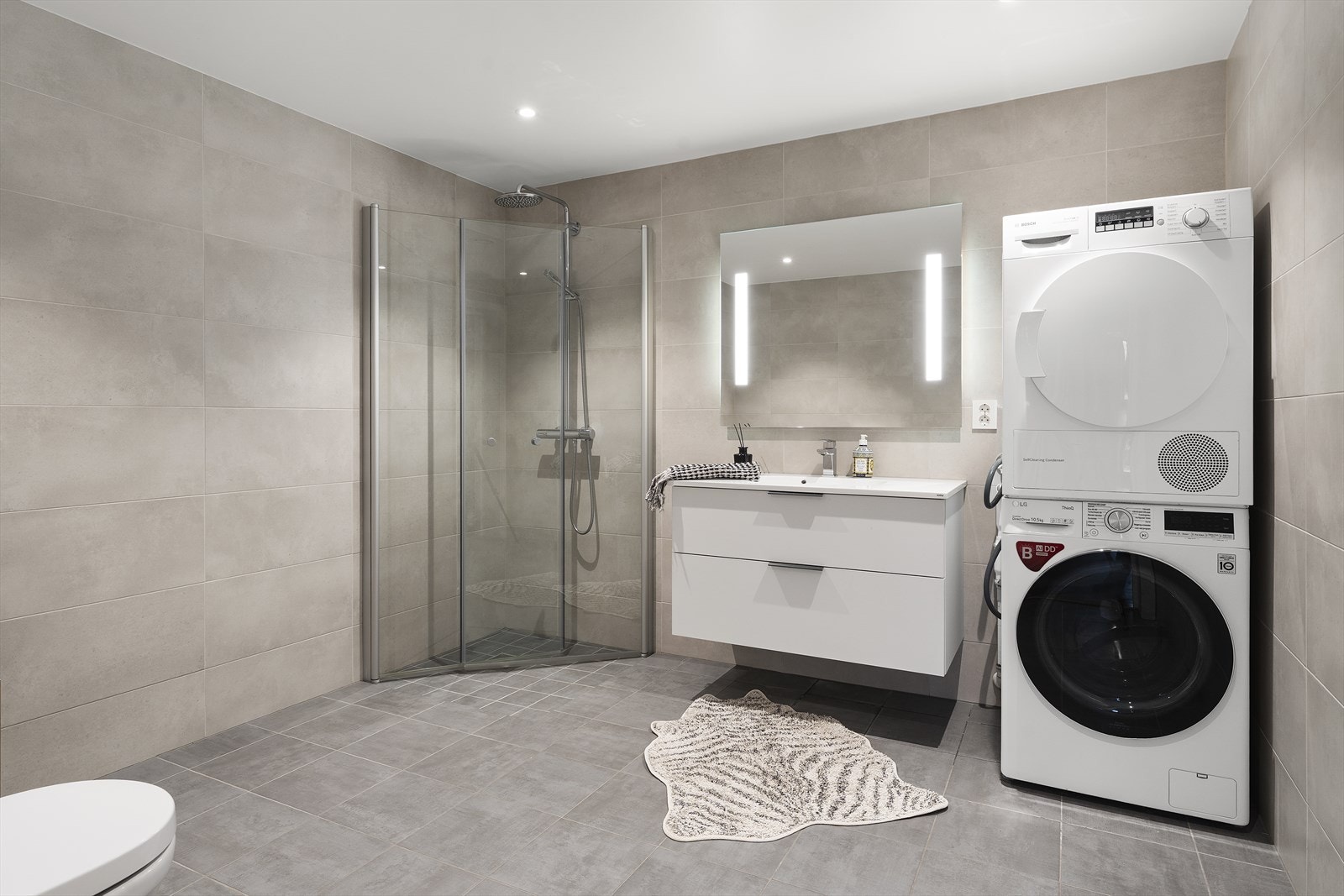 Badet er svært romslig og har gråtonede fliser på både gulv og vegger med varmekabler i gulvet. Galleribilde