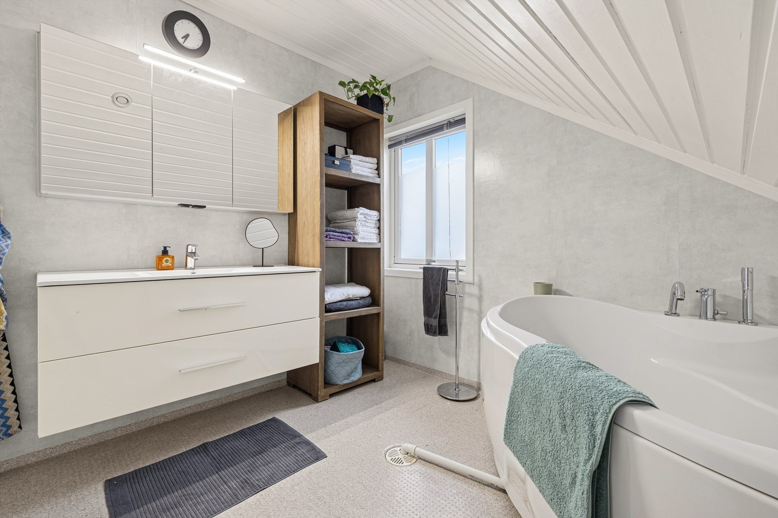 Innredning med skuffer og heldekkende servant, praktisk speilskap med belysning over, hjørnebadekar, gulvmontert toalett og mekanisk avtrekk. Galleribilde