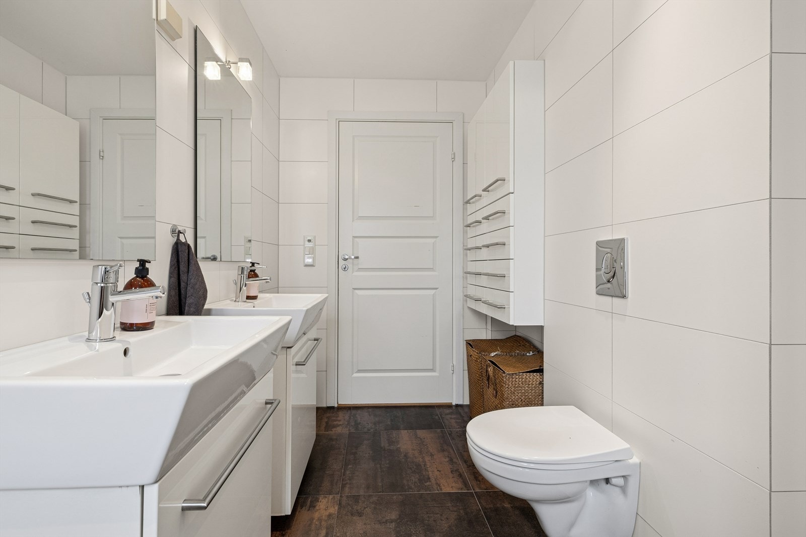 Badet innehar to servantinnredninger, speil med belysning over, veggskap, vegghengt toalett, dusjhjørne og elektrisk styrt vifte. Galleribilde