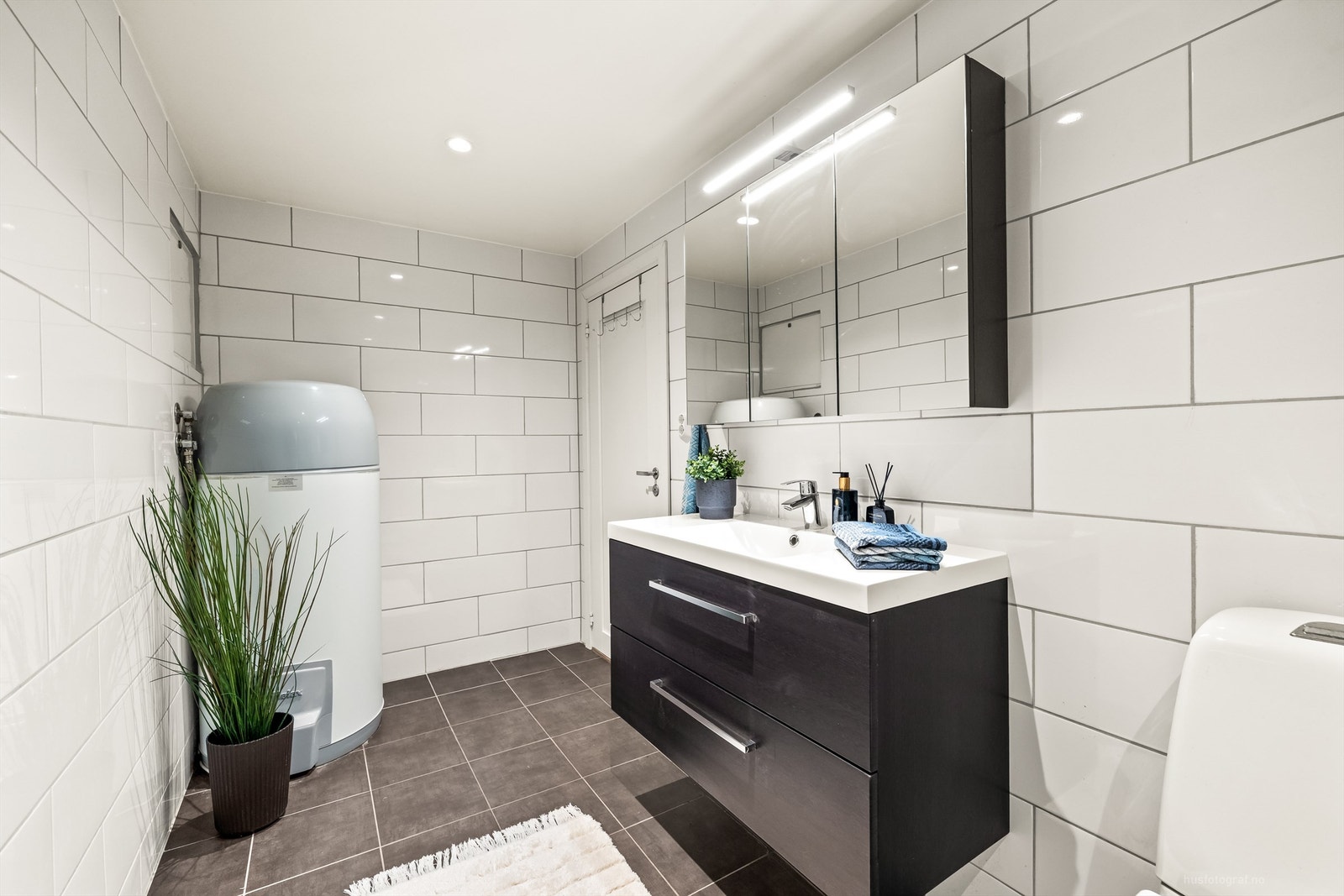 Badet har heldekkende servant over servantskap og speilskap med integrert belysning. Galleribilde