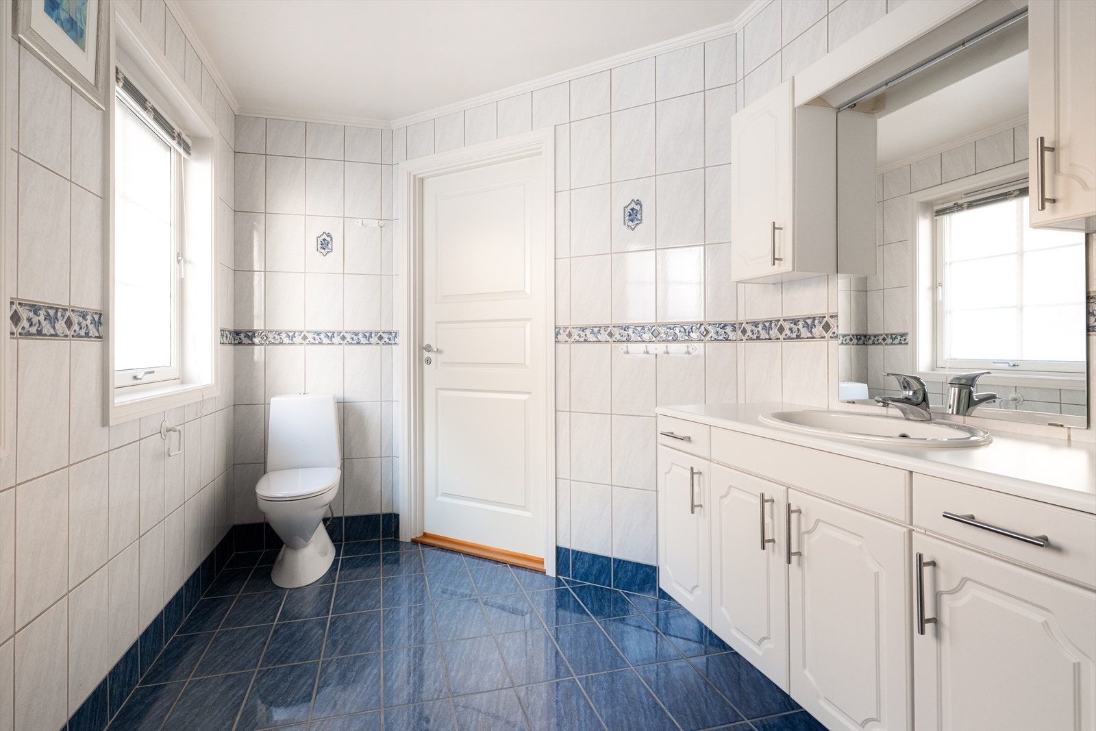 Badet er innredet med toalett, dusjkabinett og romslig servantinnredning med skuffer, skap og speil. Galleribilde