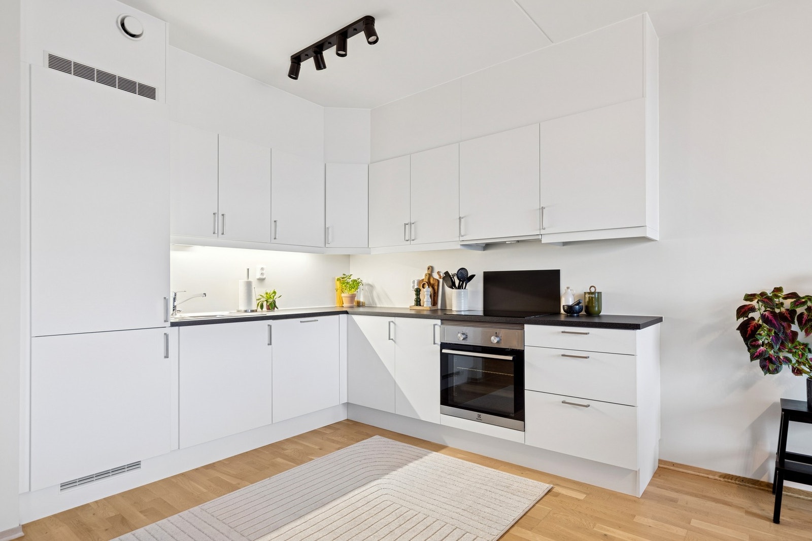 Kjøkkenet har et tidløst uttrykk med hvite fronter, integrerte hvitevarer og laminert benkeplate. Galleribilde