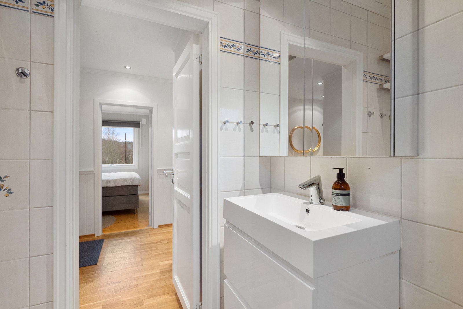 Badet har fliser i gulv og på vegger, servant med dobbel skuffeseksjon og badekar med dusj. Leiligheten har separat toalettrom. Galleribilde