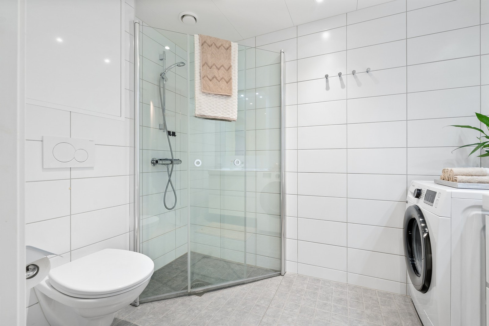 Badet er innredet med servantinnredning med slette fronter, speil med overlys, veggmontert toalett og dusjhjørne. Galleribilde