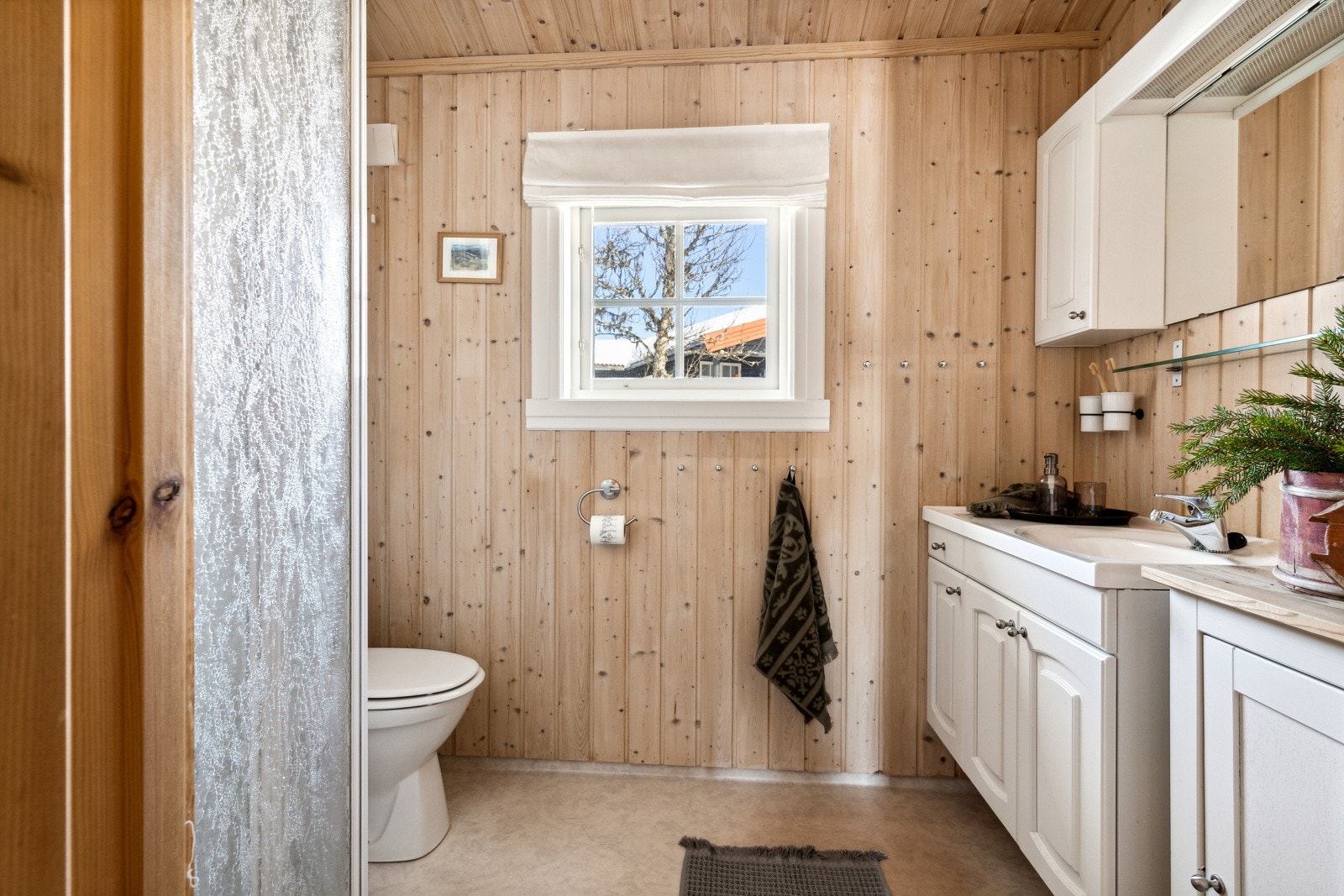 Hytta har et sjarmerende bad, som er innredet med gulvbelegg med varme og våtromsplater på vegg i dusjsonen, noe som gir en lettstelt overflate. Galleribilde