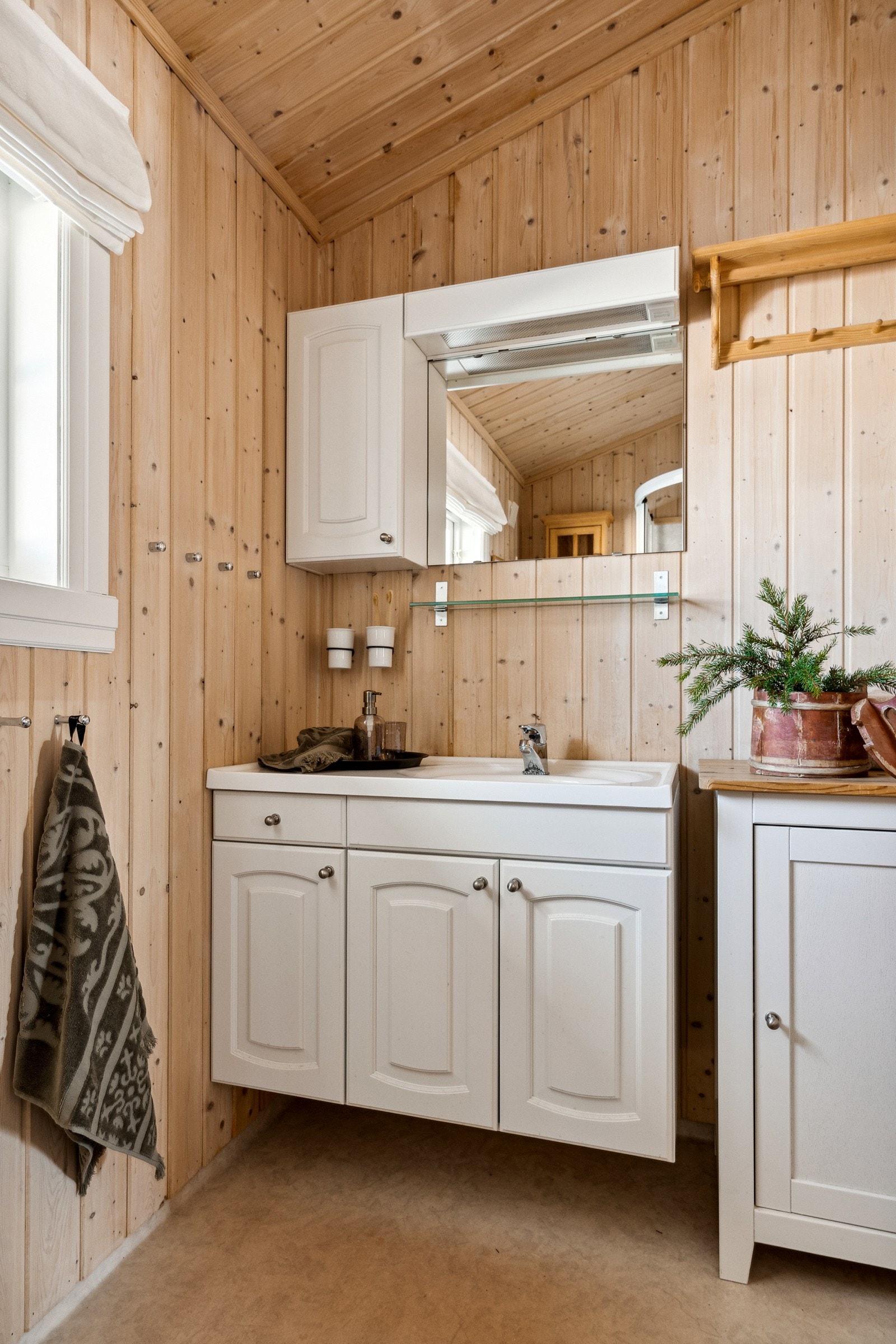 Videre er badet innredet med et gulvmontert toalett, et dusjhjørne, og en servant med et praktisk underskap, som gir deg god plass til oppbevaring av baderomsartikler. Galleribilde