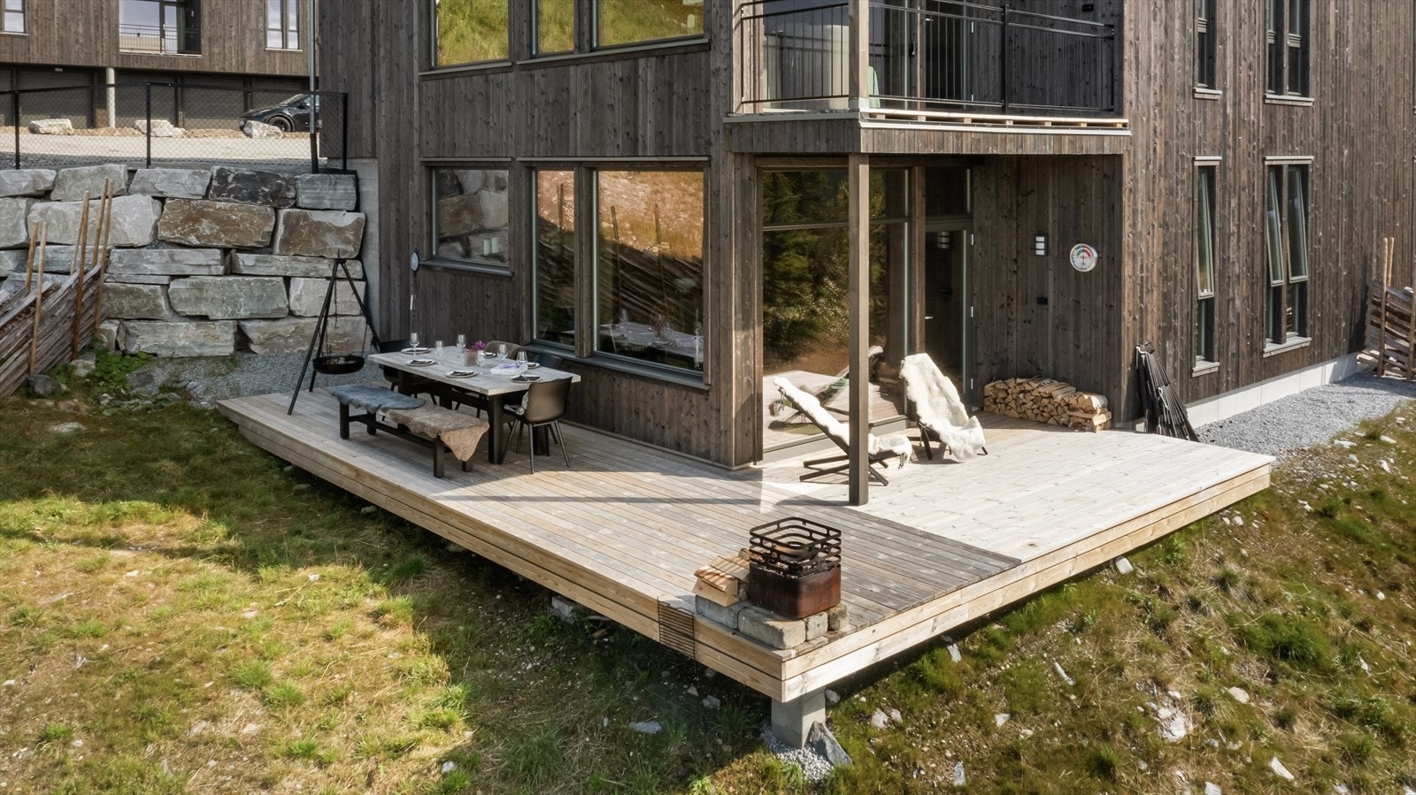 Terrenget utenfor terrassen består av gress, grus og naturlig vegetasjon som blir skjermet mot skibakken av en sjarmerende skigard. Galleribilde