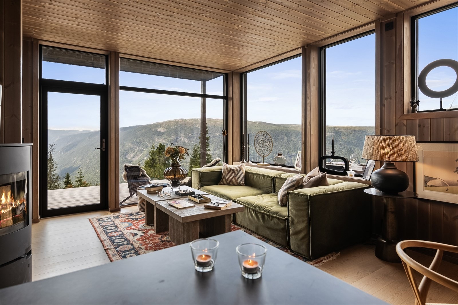 En peisovn gjør det ekstra koselig etter en dag ute i det fri, og via høye vinduer på to sider får man en formidabel utsikt, samt en tilnærmet sømløs overgang til den solfylte terrassen utenfor. Galleribilde