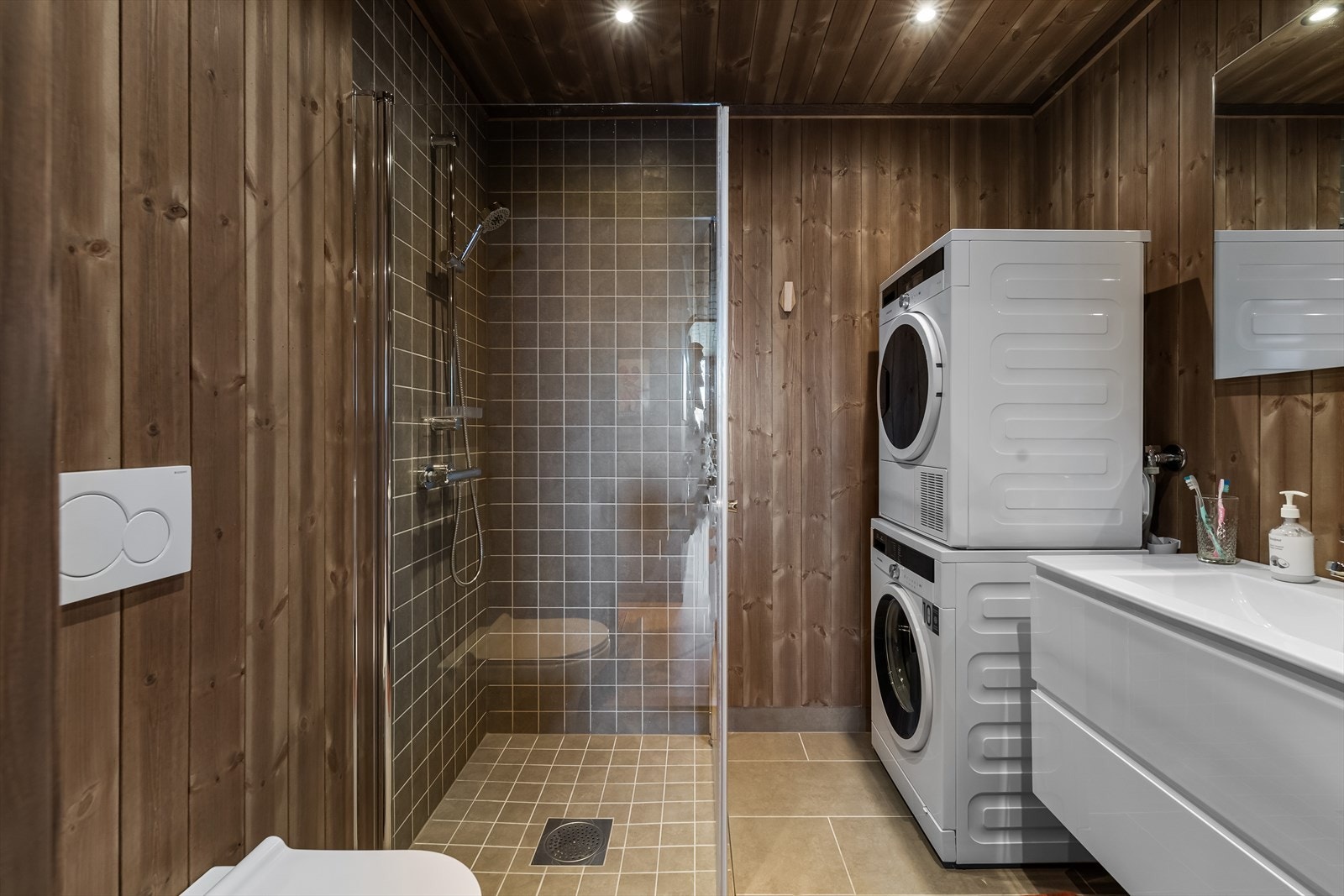 Leiligheten har to pene bad, noe som er kjekt om man er mange om plassen. Begge rommene har mørkbeiset panel på vegger og i himlingen. På gulvene, lang sokler og vegger i dusjhjørner er det grå fliser i to ulike størrelser. Galleribilde