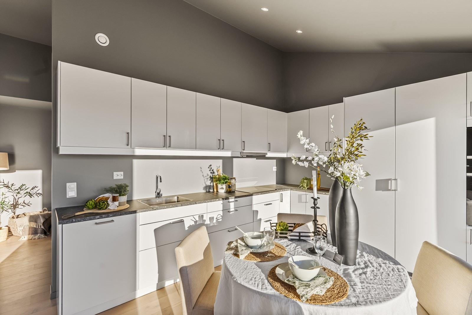 Ellers er kjøkkenet moderne og innbydende med rikelig skap- og benkeplass. Med slette fronter i lyse fargetoner og mørktonet benkeplate av laminat er kjøkkenet et praktisk og tiltalende rom. Galleribilde