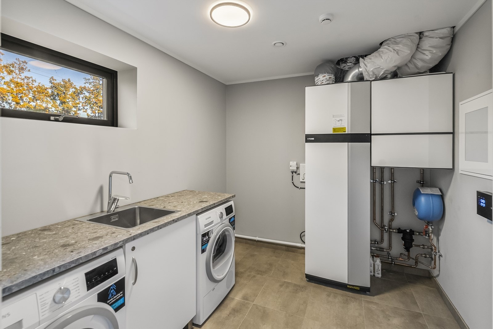 Vaskerommet er arealeffektivt og praktisk med flislagt gulv og slette overflater i lyse farger. Vaskerommet har skap- og benkeplass, opplegg for vaskemaskin og tørketrommel, samt utslagsvask og armatur. Vaskerommet er kombinert med teknisk rom. Galleribilde