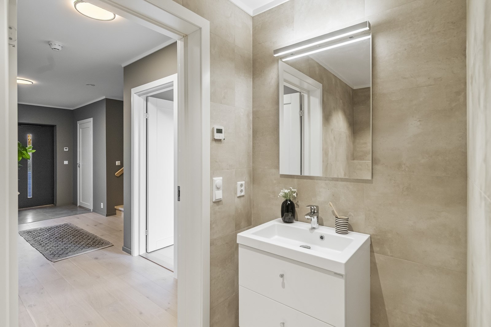 Romslig og stilrent bad med dusjnisje og regndusj-garnityr. Badet har også vegghengt toalett og servant i baderomsinnredning med overhengt speil. Dette er et bad å bli glad i! Galleribilde