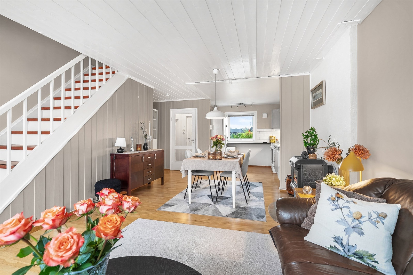 Boligen har en åpen stue- og kjøkkenløsning, med peis som skaper en lun og innbydende atmosfære Galleribilde