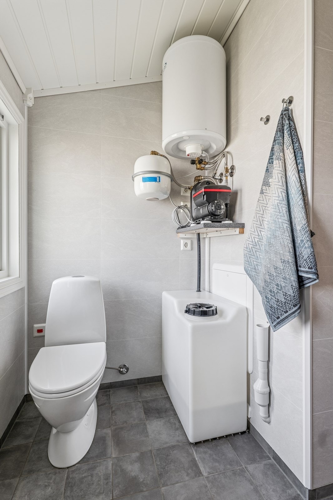 På badet finner vi også vanntanken, varmtvannsberederen og pumpen som sørger for kontinuerlig vanntrykk. Galleribilde