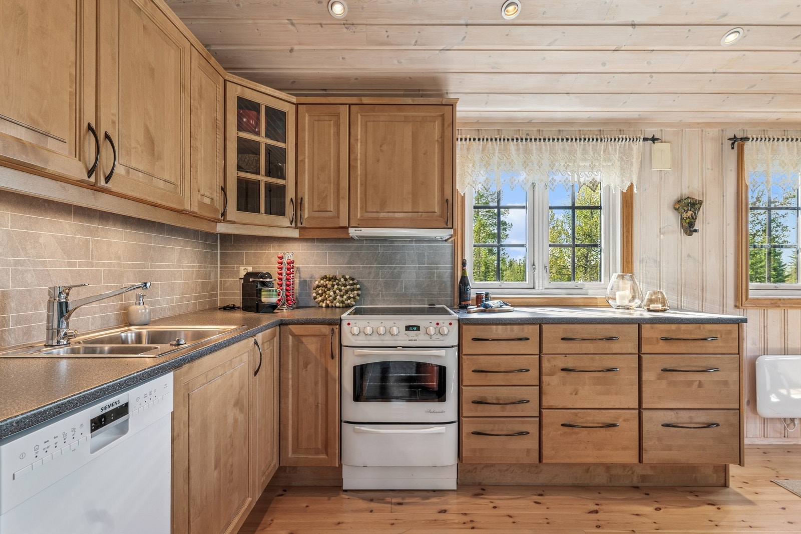 Kjøkkenet har en åpen løsning med innredning fra byggeåret, god benkeplass og frittstående hvitevarer. Galleribilde