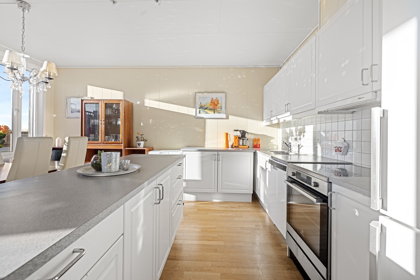 Kjøkkeninnredningen har hvite, profilerte fronter og laminert benkeplate. Galleribilde