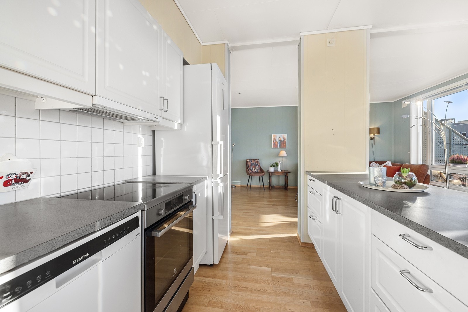 Det er fliser på vegg mellom overskap og benkeplaten, samt benkebelysning. Galleribilde