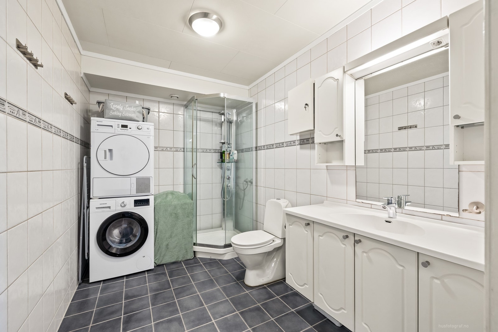 Romslig bad med dusjkabinett og sone for vaskemaskin og tørketrommel Galleribilde