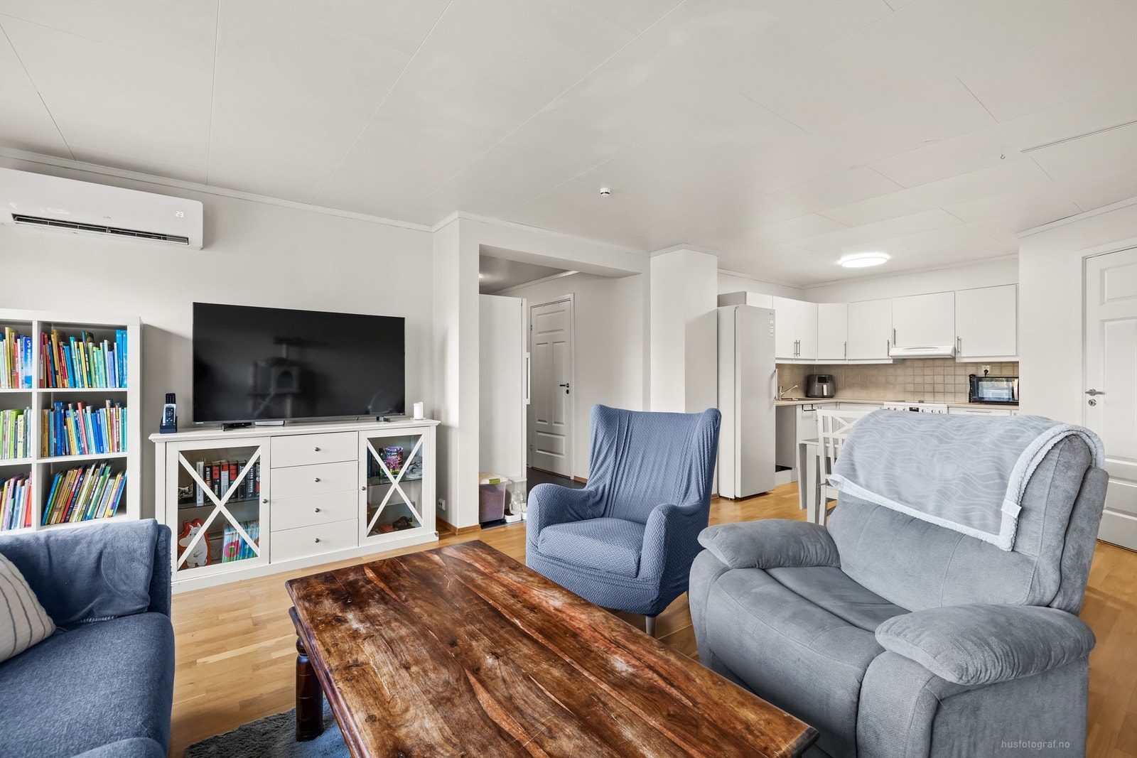 Lun stue med parkettgulv og plass til TV-løsning og flere sittegrupper. Foto: Haiman Askari/Knipzet AS Galleribilde