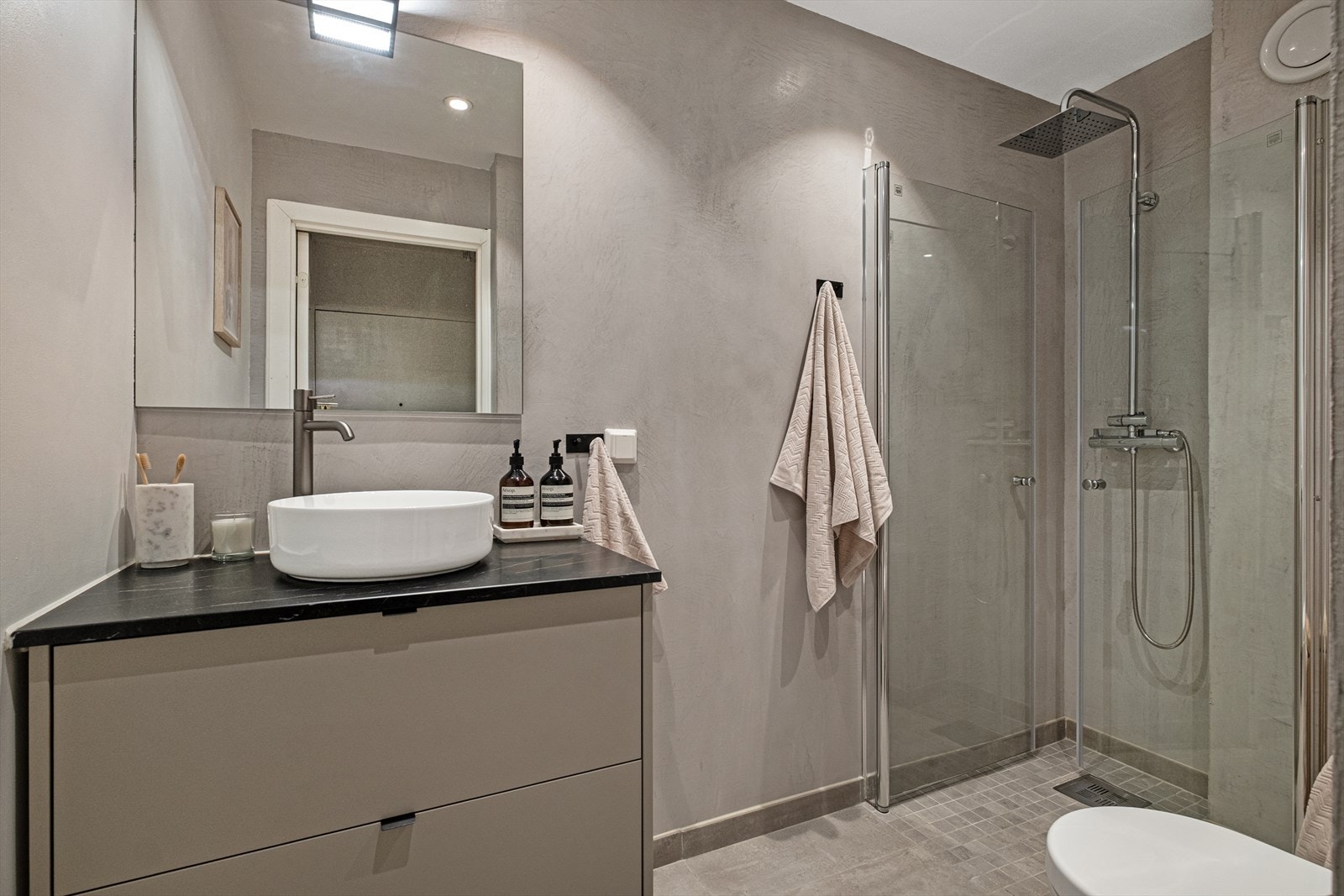 Baderom fra 2019 med microsement på veggene og flislagt gulv med varmekabler. Galleribilde