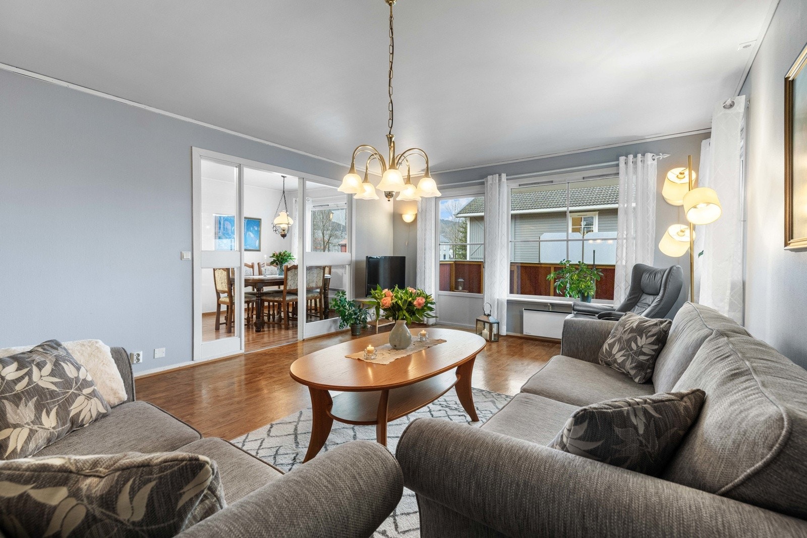 Åpen og innbydende stue med store vinduer og naturlig overgang til kjøkkenet og spisestuen. Galleribilde