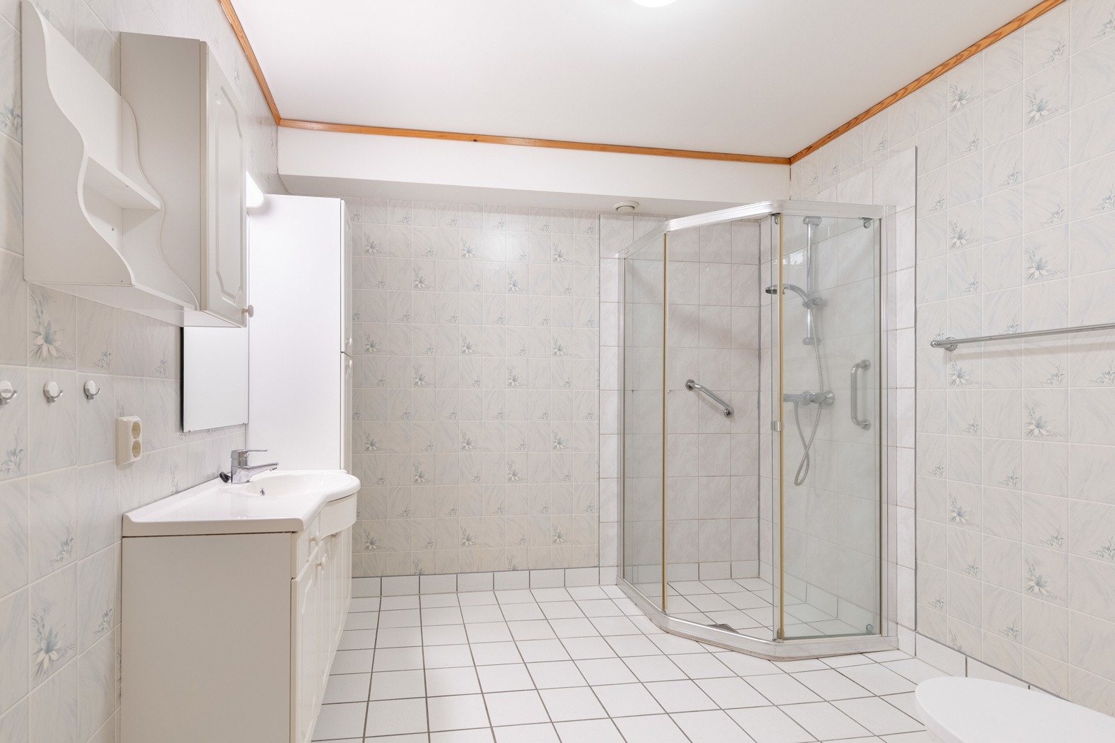 Lyst og funksjonelt baderom med flislagte overflater og stor dusjløsning. Galleribilde