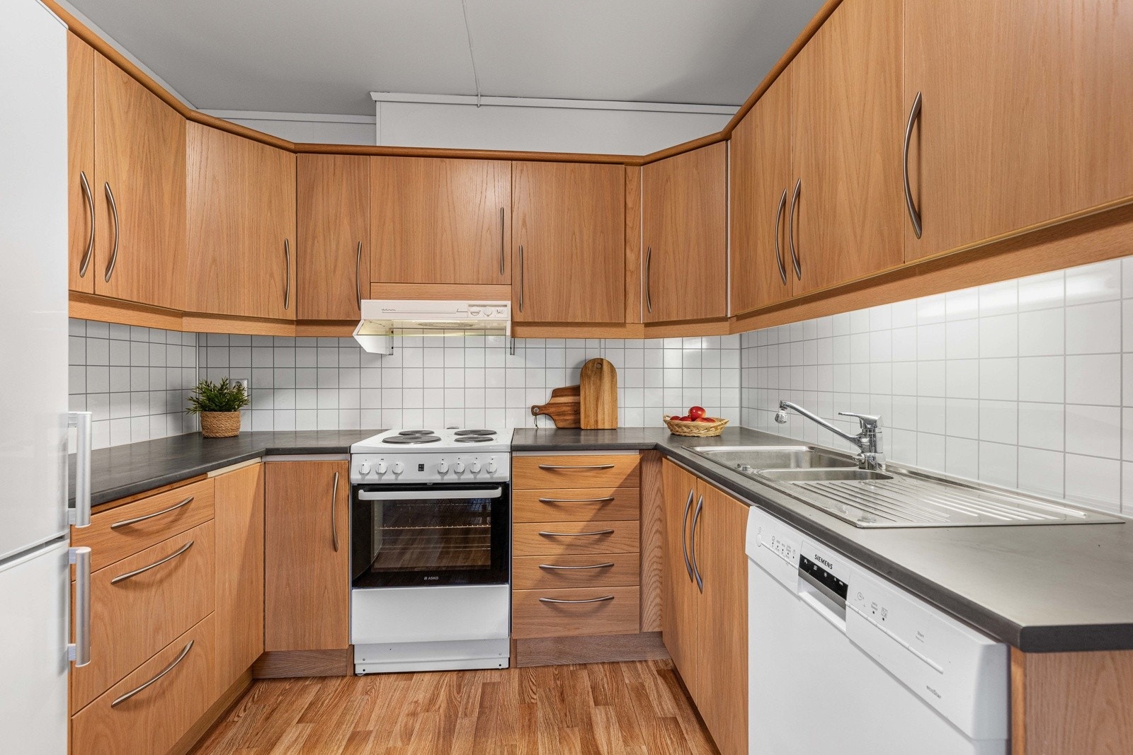 Velholdt kjøkken med rikelig skap- og benkeplass i praktisk U-formet løsning. Galleribilde