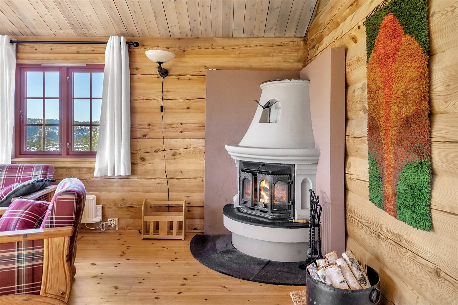 Vedfyrt peis i stuen som bidrar til både hygge og varme når gradene synker Galleribilde