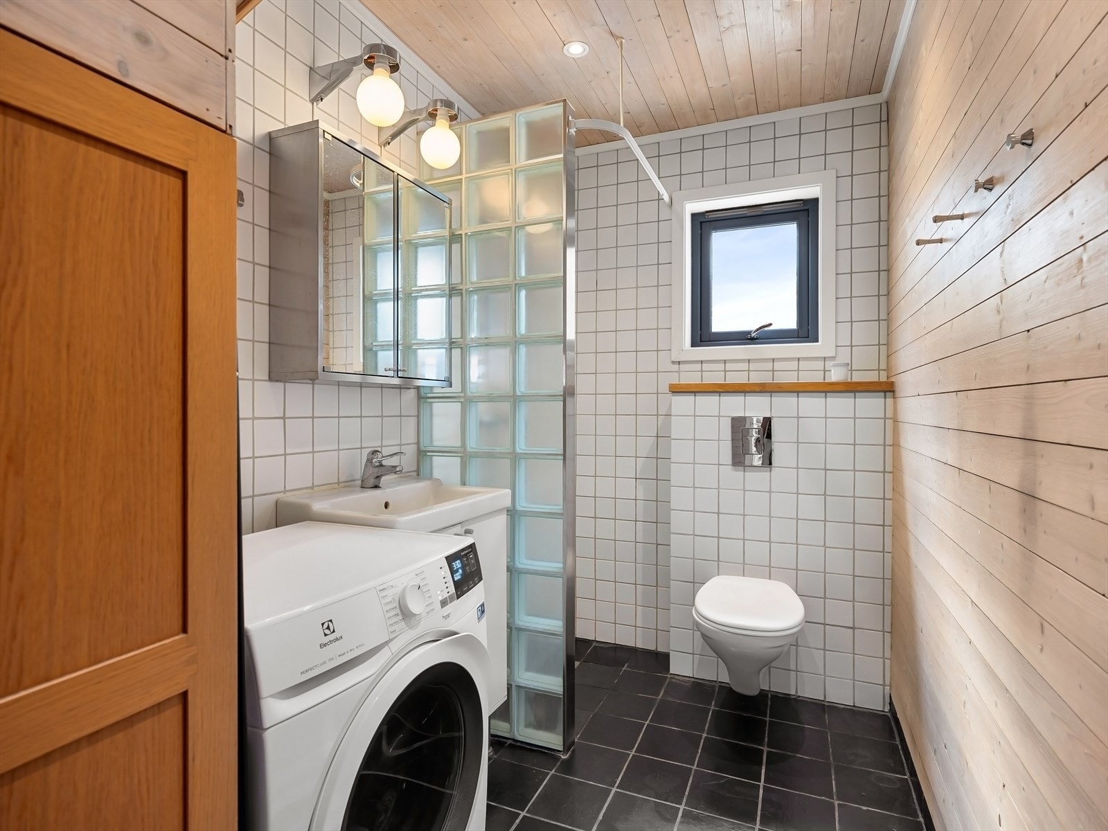 Dusjhjørne, veggfestet toalett og opplegg for vaskemaskin Galleribilde