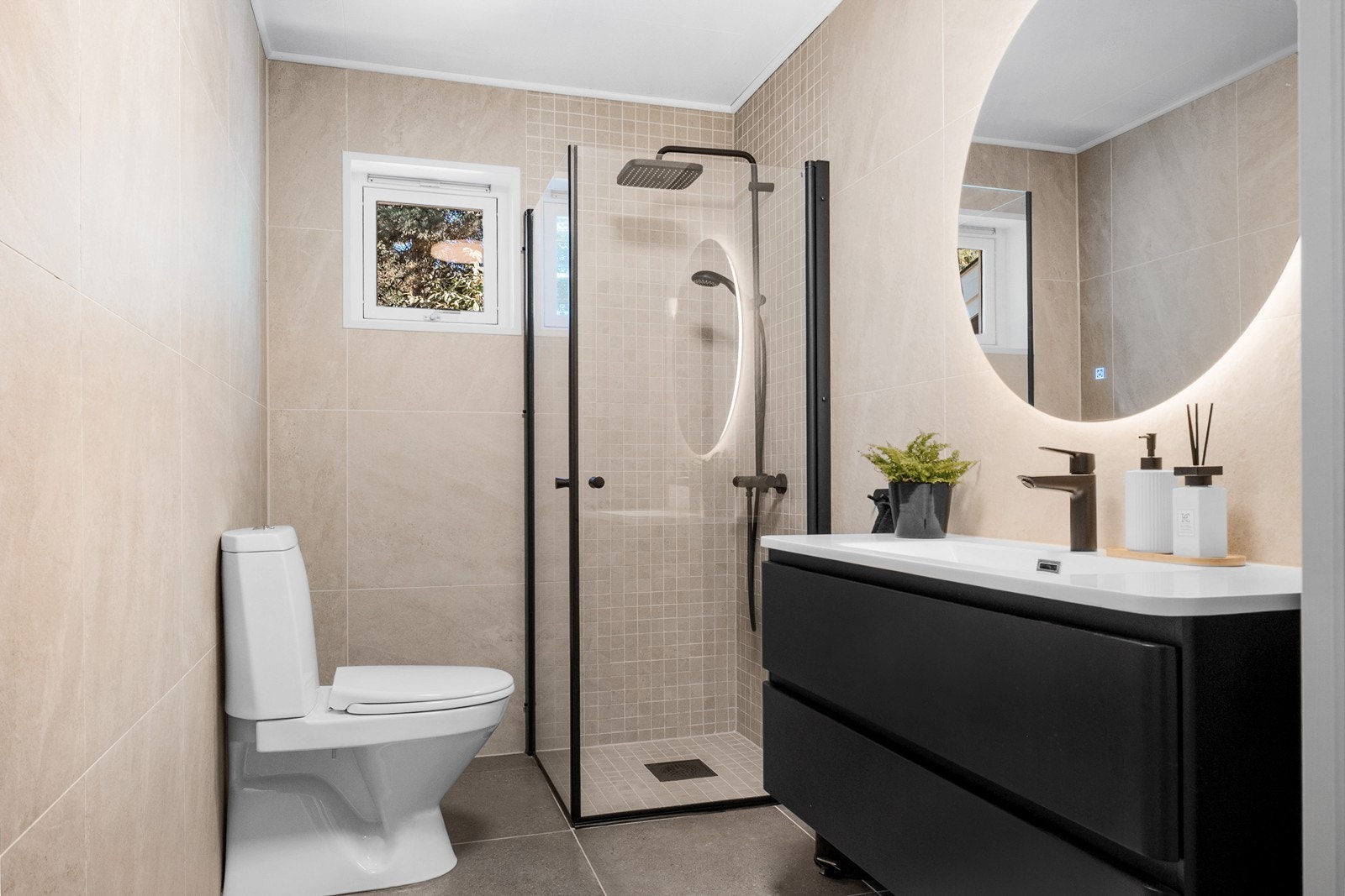 Badet ble oppgradert i 2023 med flis på flis. Rommet har moderne 60x60 fliser på vegger og gulv, samt mosaikkfliser i dusjsonen. Galleribilde