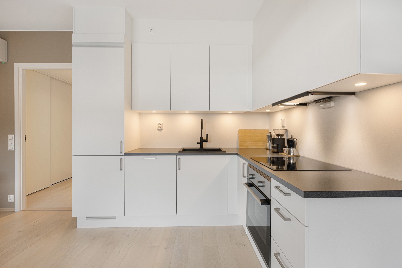 Kjøkkeninnredningen er i L-form med glatte fronter Galleribilde