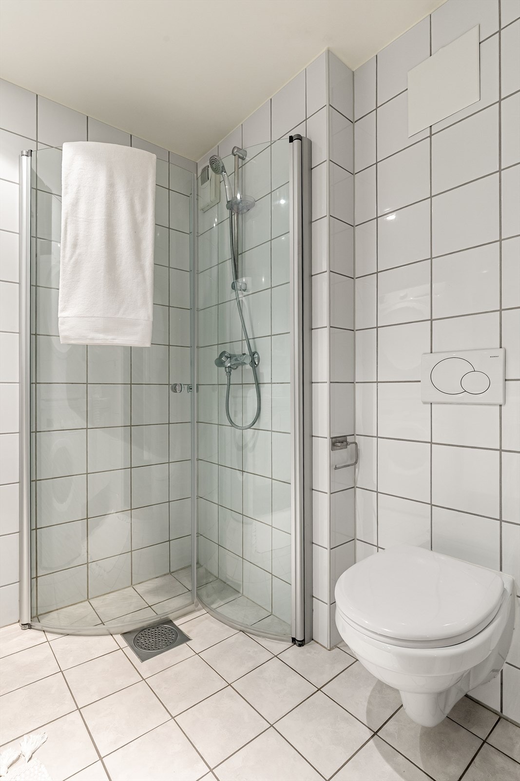 Badet er videre innredet med vegghengt toalett, dusjhjørne med innfellbare dusjdører i glass Galleribilde