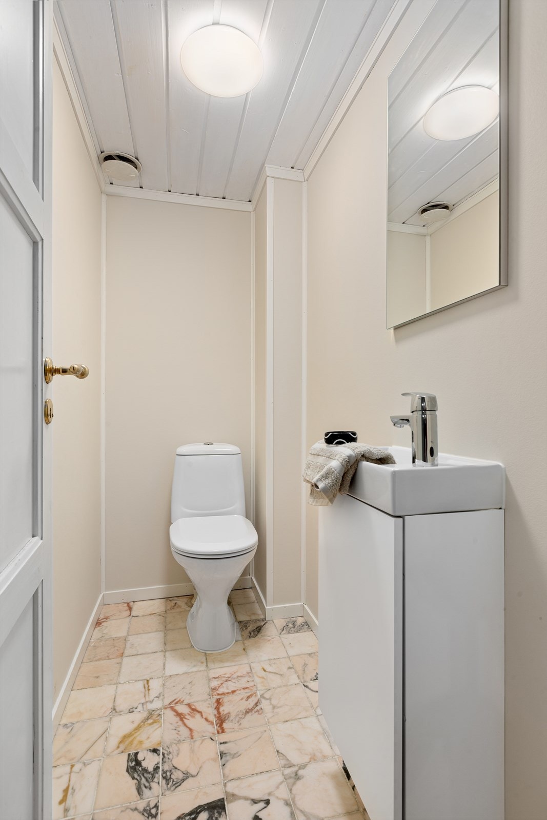 Separat toalett med flis på gulv og vegghengt servantinnredning Galleribilde