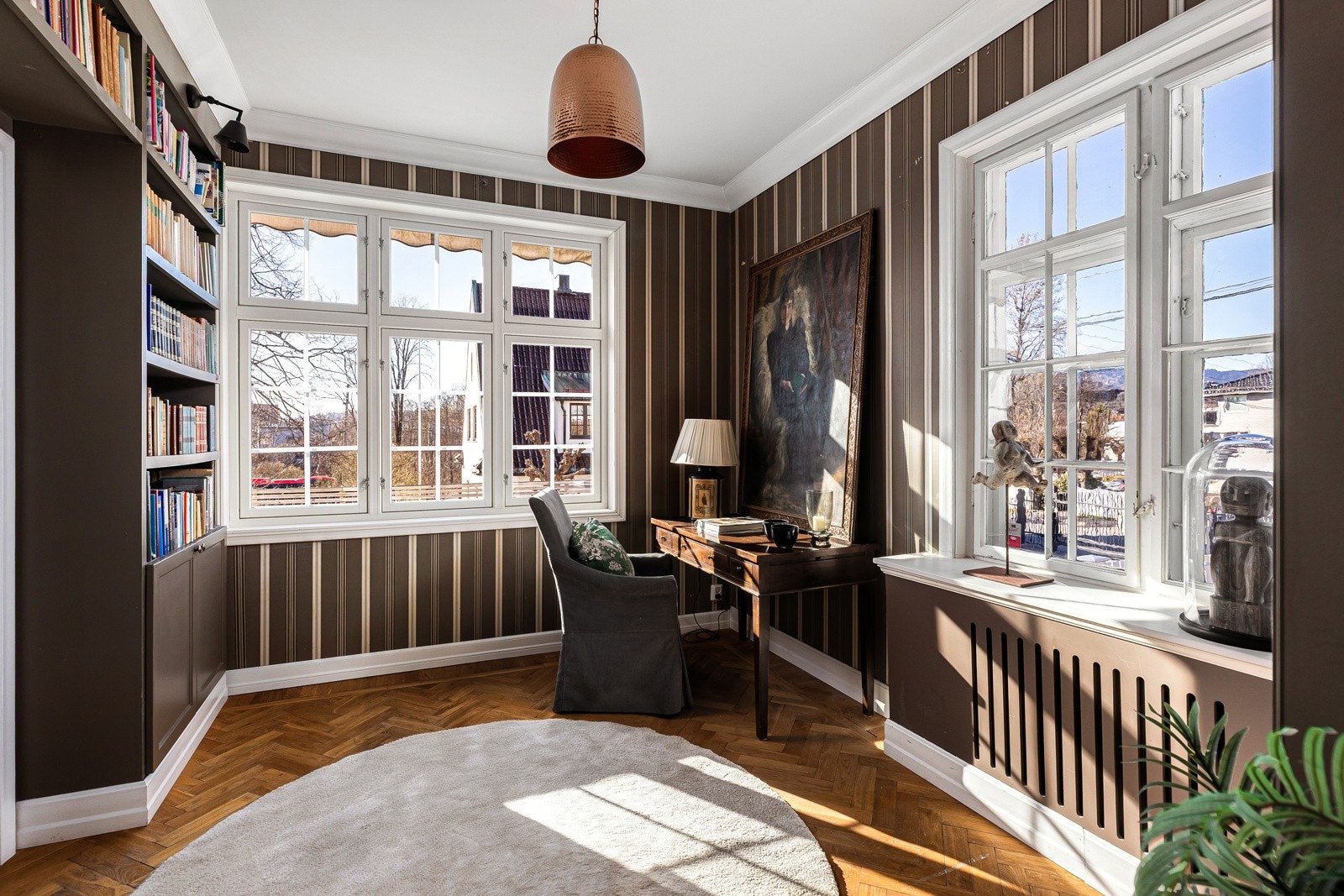 Biblioteket er stilig innredet med pen tapet på veggene og plassbygd bokhylle.