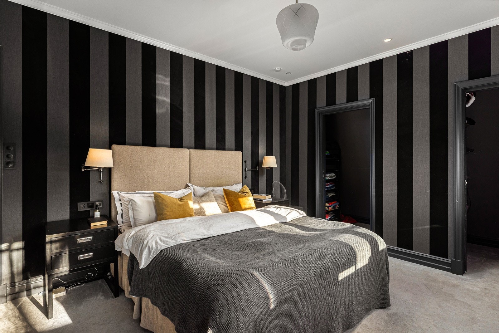 Stort hovedsoverommer har vegg-til-vegg teppe på gulv og tapet på veggene.