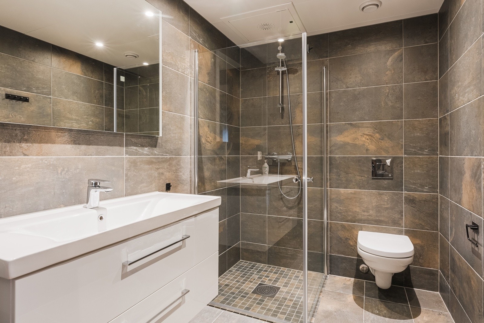 I leiligheten er det to store og flislagte baderom i samme preg som gir en helhetlig og lun følelse. Begge soverom med vegghengt wc, pen innredning og dusjhjørne. Det er varme i gulvet og downlights i tak. Galleribilde