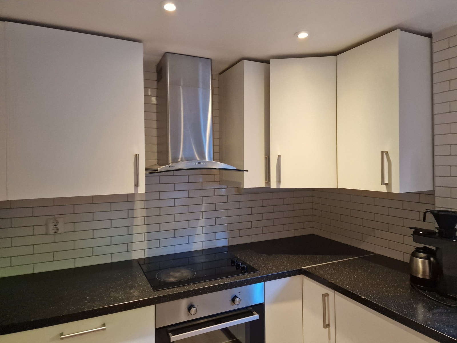 Lyst kjøkken med koketopp, ovn, oppvaskmaskin og kjøleskap/frys. Galleribilde