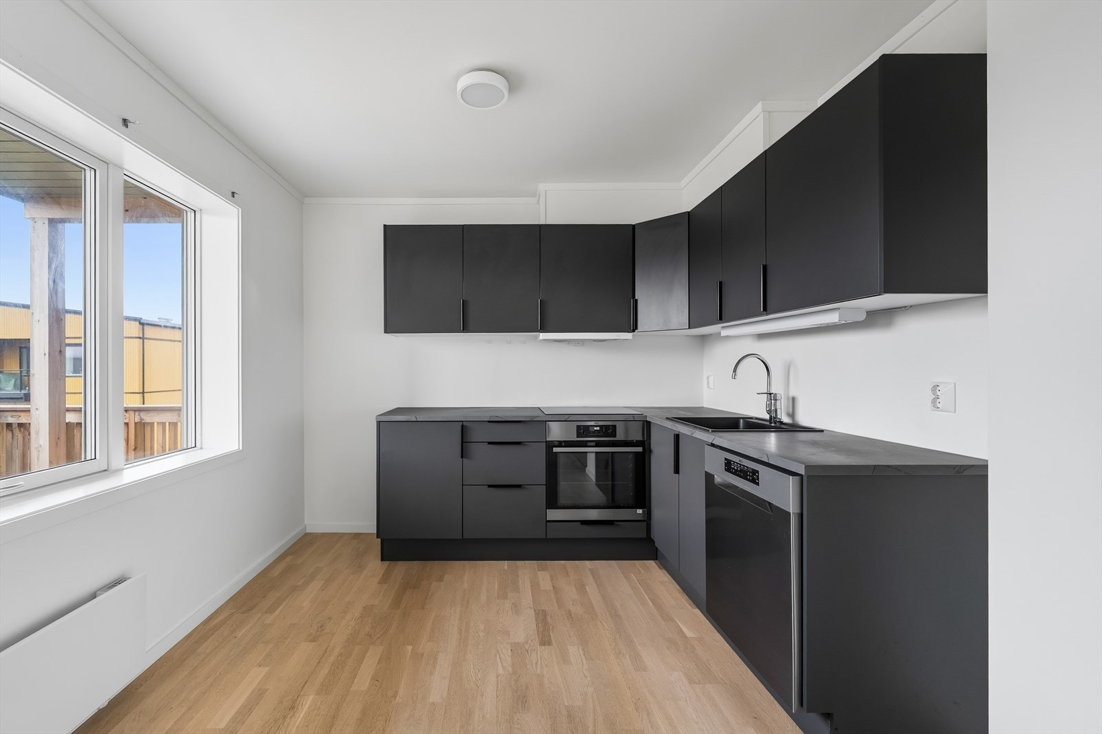 Kjøkkeninnredningen har sorte, glatte fronter og laminert benkeplate. Galleribilde